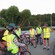 A group of people wearing safety vests and helmets stand with their bicycles listening to a guide